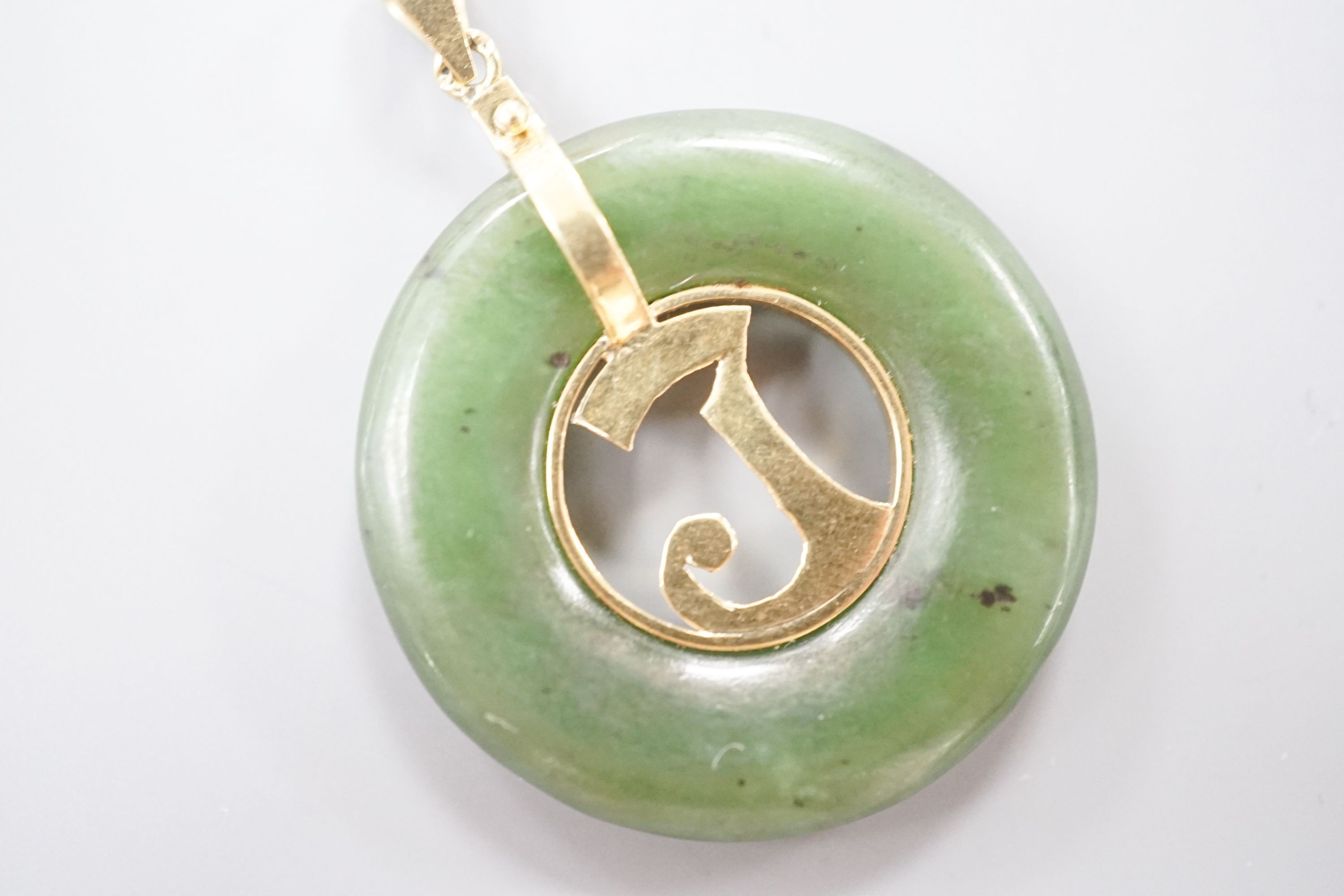 A yellow metal mounted pierced circular nephrite pendant, diameter 29mm, gross weight 8.5 grams.